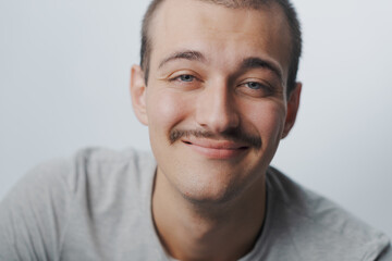 Naklejka premium Close-up portrait of a young man with mustache smiling softly at camera