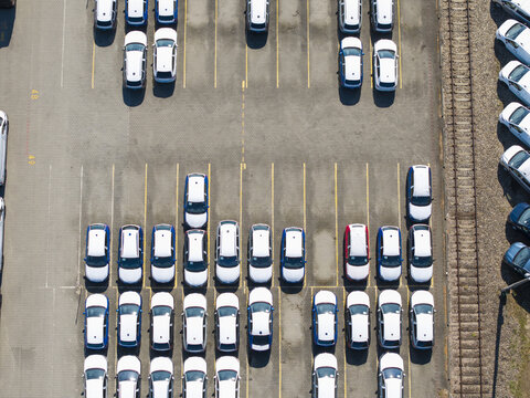 Aerial view of an automotive logistics terminal with rows of new cars parked in a large paved lot in Poland.