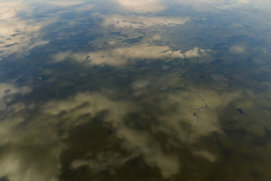 Aerial view of a vast landscape with scattered water bodies and cloud shadows cast over the terrain in Greece.