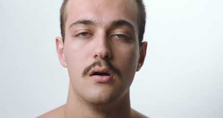 Fototapeta premium Frontal Close-Up Studio Portrait of Exhausted Young Man Sweating from Extreme Heat