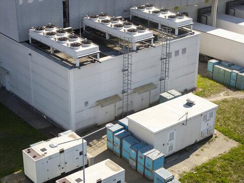 Aerial view of an AI data center cooling system with industrial fans on the roof, auxiliary power units, and equipment containers in Krakow, Lesser Poland Voivode, Poland.