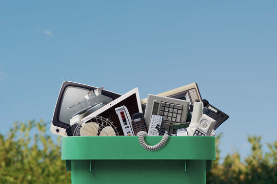Electronic Waste Recycling Concept with Discarded Devices in Green Bin Outdoors