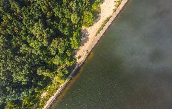 Aerial view of Mewia Lacha Reserve featuring a sandy beach bordering a dense forest and the calm waters of the Baltic Sea in Gdansk, Pomeranian Voivodeship, Poland.