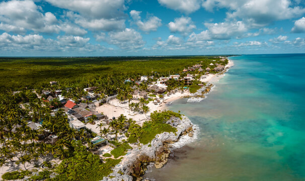 Aerial view of the Tulum coastline featuring rocky cliffs, sandy beaches, palm trees, and coastal buildings in Tulum, Quintana Roo, Mexico.