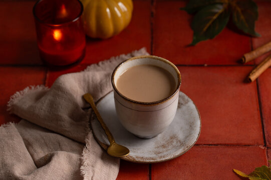 Cozy masala chai latte in a ceramic cup with autumn decor on a rustic table