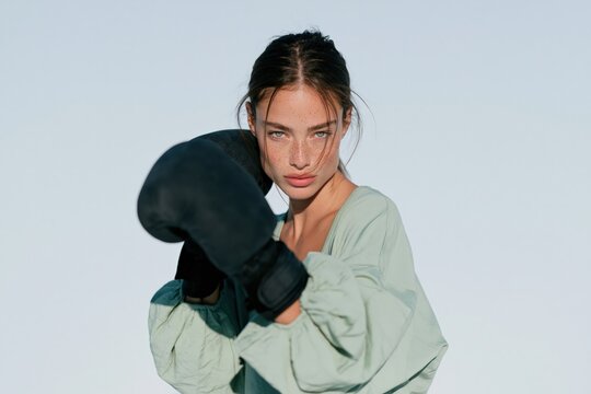 Midshot female boxer throwing a jab with teal sweatshirt and black gloves for sports banner background and fitness advertising