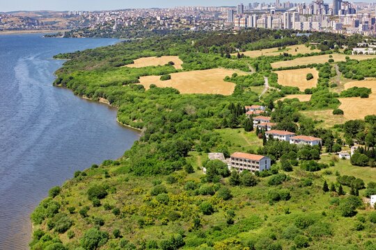 Aerial view of the lush green landscape and residential buildings along the shores of Kucukcekmece Lake with the modern city skyline in Kucukcekmece, Istanbul, Turkey.
