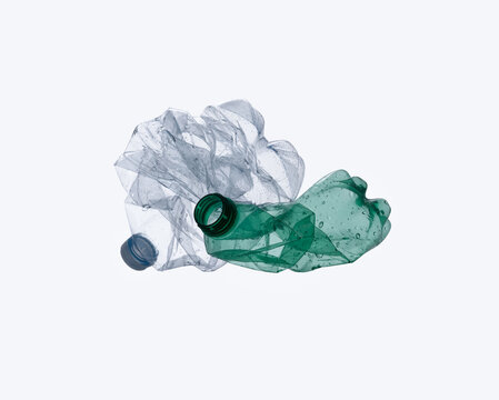 Crushed clear and green plastic bottles isolated on light background for recycling concept