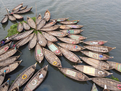 Aerial view of numerous wooden boats arranged in a circular pattern on the Buriganga River in Dhaka, Bangladesh.