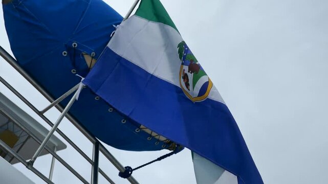 Galapagos Islands flag and coat of arms with iconic giant tortoise symbol waving in the wind on back of ship