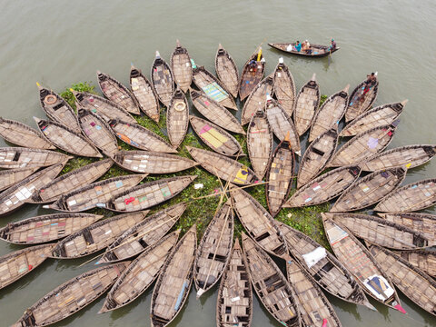 Aerial view of wooden boats arranged in a circular pattern on the Buriganga River in Dhaka, Bangladesh.
