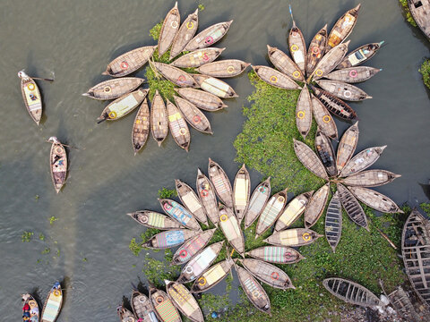 Aerial view of wooden boats arranged in flower-like patterns on the Buriganga River in Dhaka, Bangladesh.