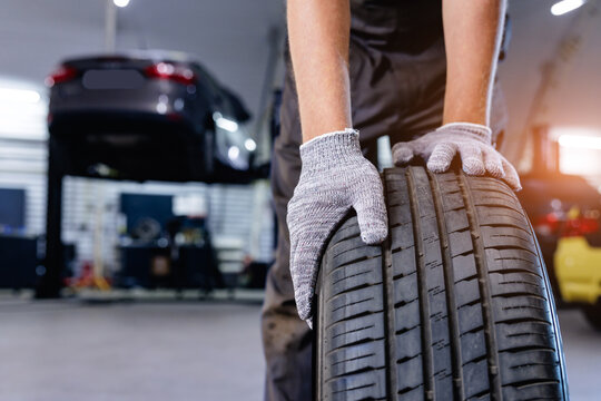 Mechanic handling car tire while standing in repair garage, fix service for wheels