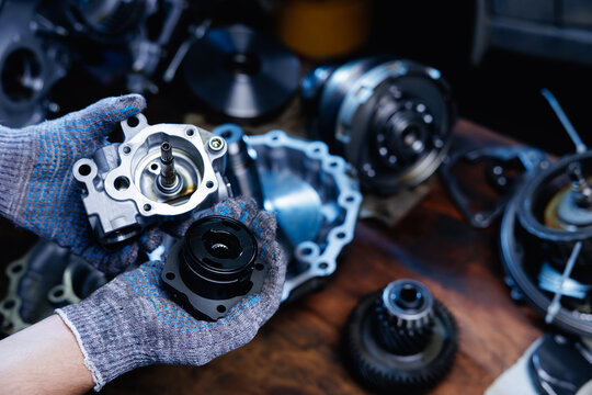 Mechanic examining transmission components on wooden workbench