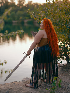 Plus Size Redhead Warrior Woman Standing With Sword By Lake