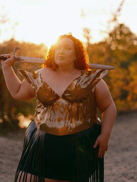 Plus Size Redhead Warrior Woman Carrying Sword On Shoulders at Sunset