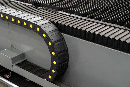 Industrial cable carrier chain mounted on a CNC machine, flexible energy chain protecting cables and hoses during automated movement in a modern manufacturing and metalworking system