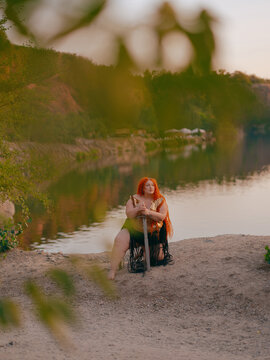 Plus Size Redhead Warrior Woman Kneeling Holding Sword by Lake