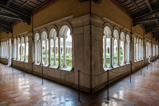 Corner view of the medieval cloister arcades with marble columns surrounding an inner courtyard garden at the Basilica of Saint Paul Outside the Walls in Rome Italy