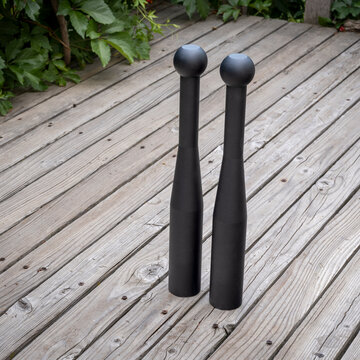 pair of heavy steel clubs on a wooden deck - functional fitness concept, heavy clubs are particularly valuable for grip strength, shoulder work, and rotational core power