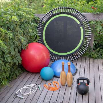 Indian clubs, mini trampoline for fitness exercising and rebounding, slam ball Swiss and balance ball, kettlebell, resistance band and jump rope in a backyard