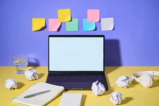 A modern workspace with a laptop, sticky notes, and paper