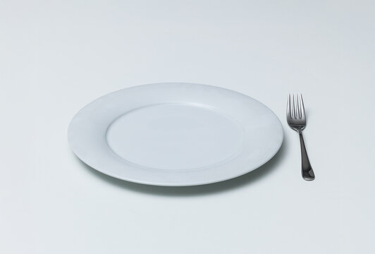 Empty Ceramic Plate with Silver Fork on White Background
