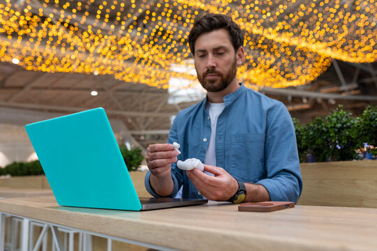 A man takes the earbuds out of the case.