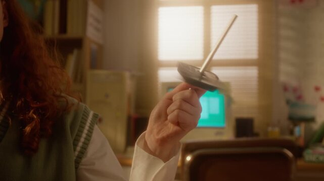 Cropped shot of unrecognizable teenager spinning floppy disk on pen in retro bedroom. Ideal for nostalgic technology commercials, 90s themed marketing, educational videos about digital history