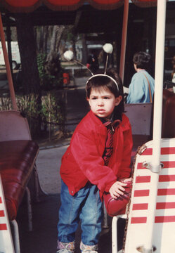 Young child wearing antennae headband riding amusement park ride