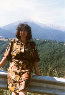 Woman posing on mountain road barrier enjoying nature