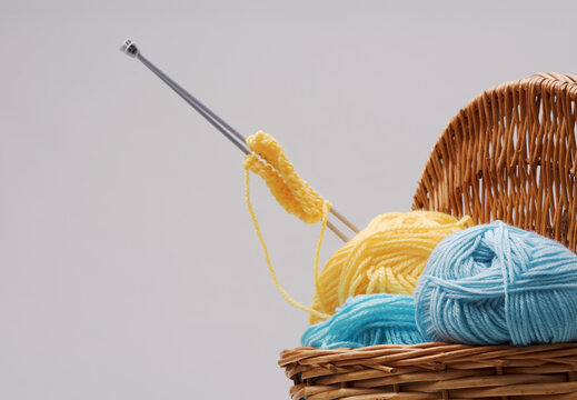 Close up of knitting needles and yellow yarn sample in wicker basket