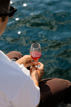 Tourist enjoying wine by a canal in Copenhagen on a sunny day.