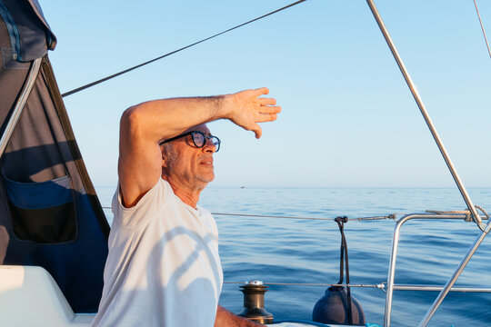 Mature man shading eyes sailing tranquil ocean