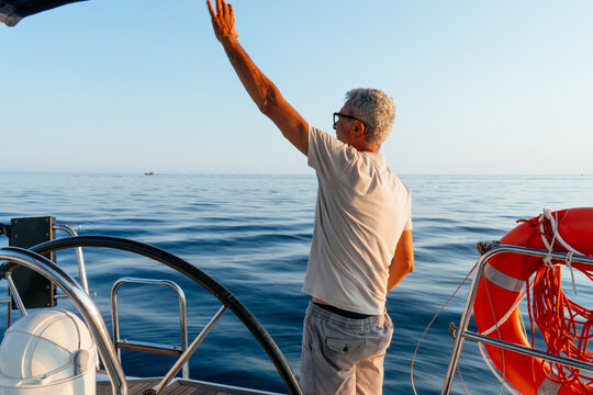 Senior man waving hand from sailing yacht