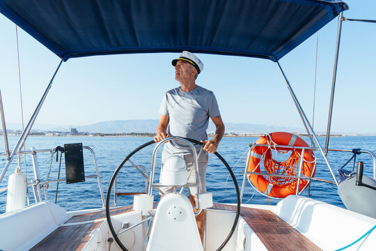 Senior man sailing yacht steering wheel on sea