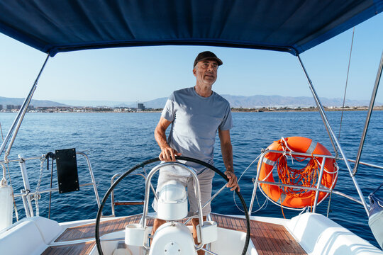 Senior man steering sailing boat enjoying ocean leisure vacation