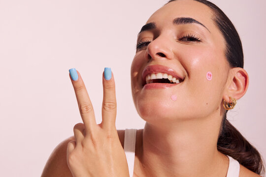 Smiling Person Shows Peace Sign With Skincare Stickers on Face