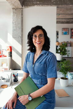 Smiling Female Professional Holding Weekly Planner In Office