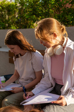 Two students studying together outdoors with notebooks