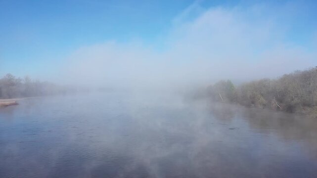A tranquil winter scene showing dense morning mist rising from the surface of the Loire River near La Charite-sur-Loire, Bourgogne-Franche-Comte, France.