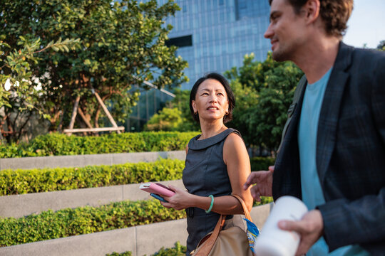 Business professionals talking while walking in an urban park
