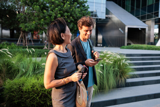 Two colleagues smiling while chatting outdoors at sunset.