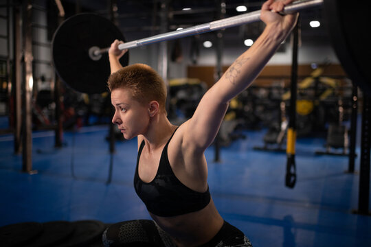 Serious sportswoman lifting barbell during training