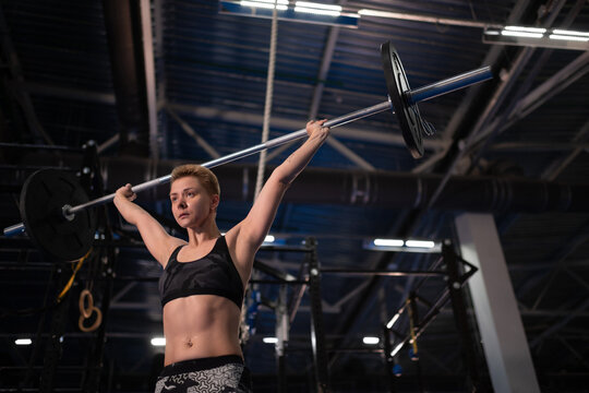 Focused female athlete exercising with barbell