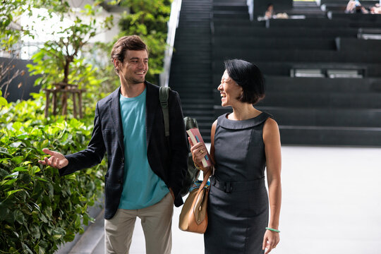 Two colleagues laughing while walking through a bright office atrium