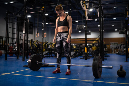 Athlete standing near barbell and preparing for deadlift 
