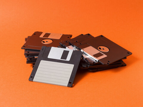 Pile of Retro Floppy Disks with Blank Label on Orange Surface