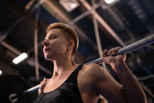 Tired sportswoman preparing to squat with with barbell