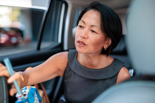 A focused Asian woman saying direction to a taxi driver
